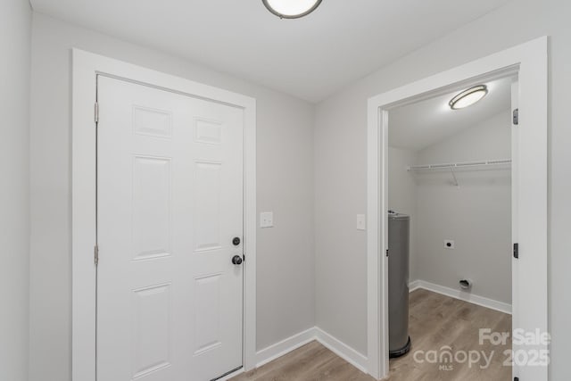 laundry room featuring laundry area, baseboards, light wood-type flooring, electric dryer hookup, and water heater