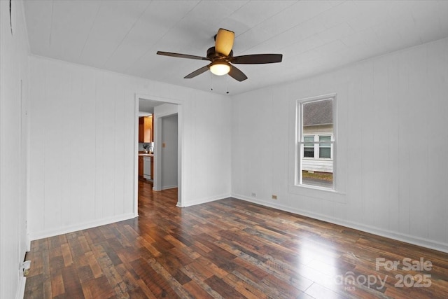 unfurnished room featuring dark wood-style floors, ceiling fan, and baseboards