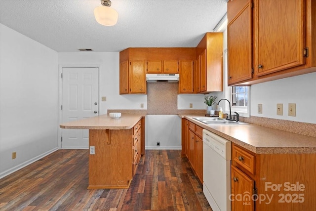 kitchen with brown cabinets, dark wood-type flooring, white dishwasher, a sink, and under cabinet range hood