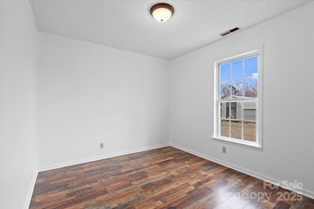 spare room with visible vents, a textured ceiling, baseboards, and wood finished floors