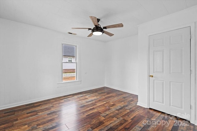 spare room featuring baseboards, dark wood-style flooring, visible vents, and a ceiling fan