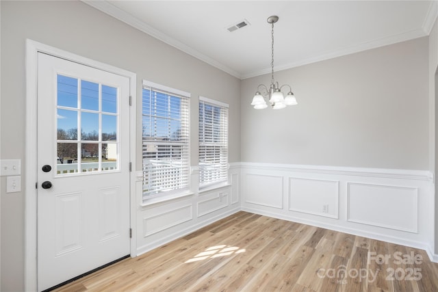 unfurnished dining area with a chandelier, visible vents, light wood finished floors, and ornamental molding