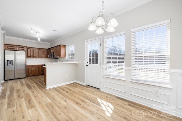 kitchen featuring light countertops, crown molding, light wood-type flooring, and stainless steel appliances