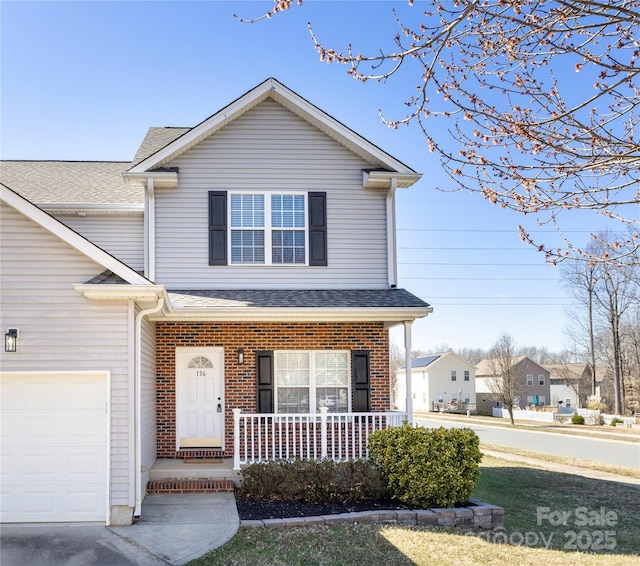 traditional home with brick siding, covered porch, an attached garage, and a shingled roof