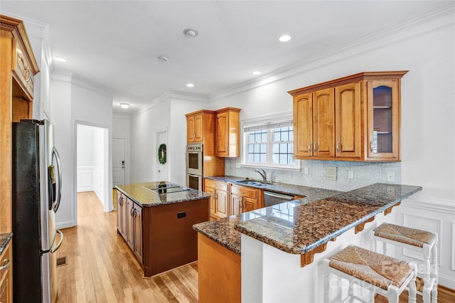 kitchen with a sink, dark stone countertops, tasteful backsplash, a center island, and appliances with stainless steel finishes