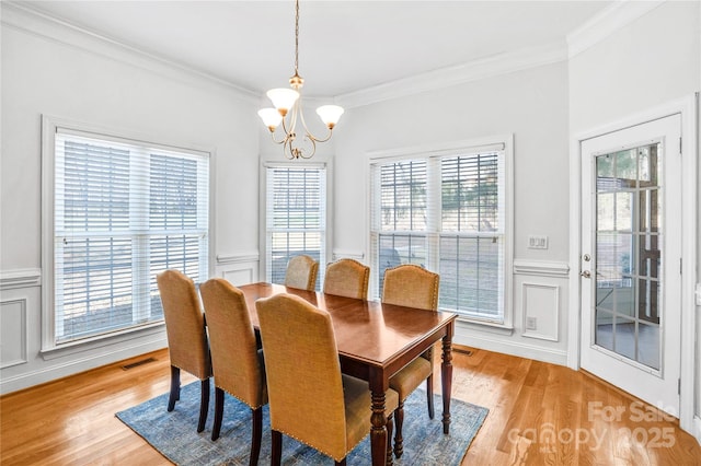 dining area featuring a chandelier, visible vents, crown molding, and light wood-type flooring