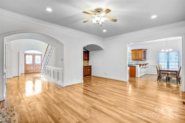 unfurnished living room with a wealth of natural light, arched walkways, and light wood-style floors