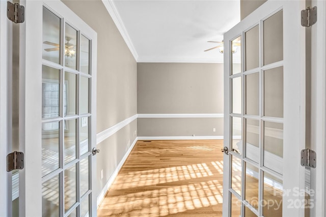 interior space with french doors, baseboards, wood finished floors, and ornamental molding