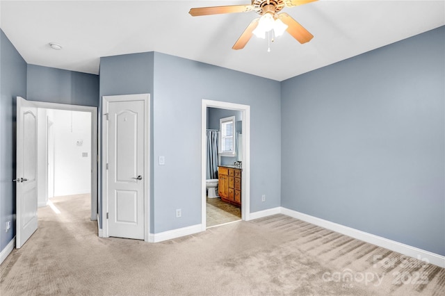 unfurnished bedroom featuring ceiling fan, baseboards, light carpet, and ensuite bath