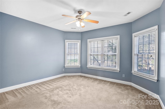 carpeted empty room with visible vents, baseboards, and ceiling fan