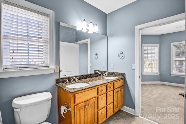 full bathroom featuring a sink, baseboards, toilet, and double vanity