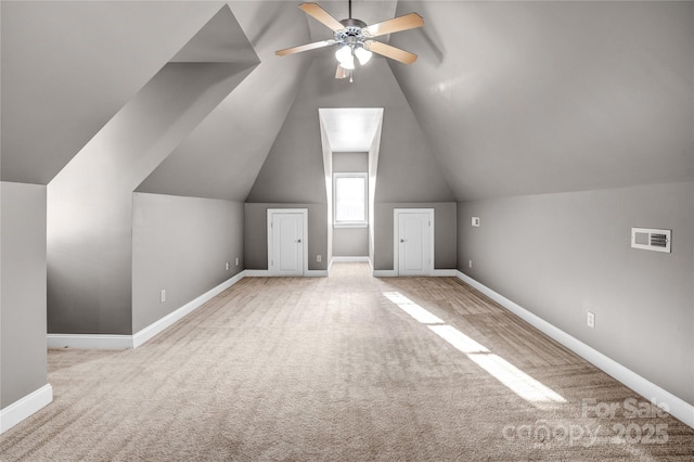 additional living space featuring visible vents, baseboards, light colored carpet, and vaulted ceiling