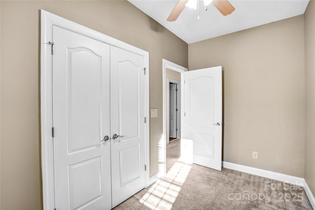 unfurnished bedroom featuring light carpet, ceiling fan, a closet, and baseboards