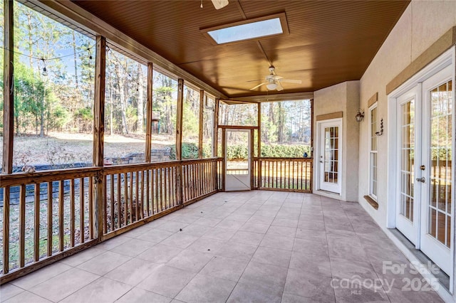 unfurnished sunroom featuring wooden ceiling, a skylight, french doors, and a ceiling fan