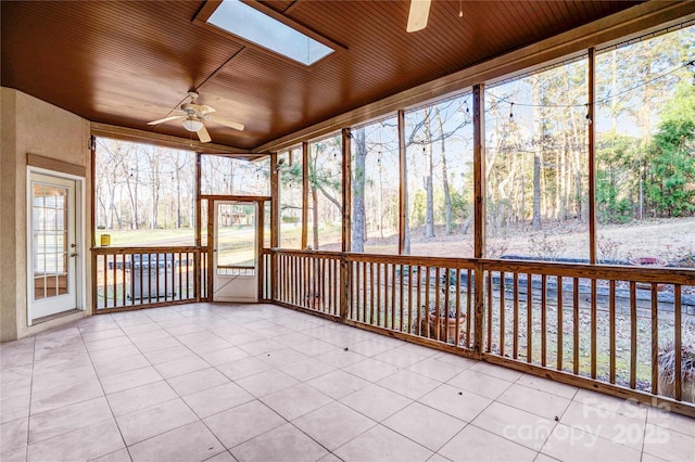 unfurnished sunroom featuring a skylight, ceiling fan, and wooden ceiling