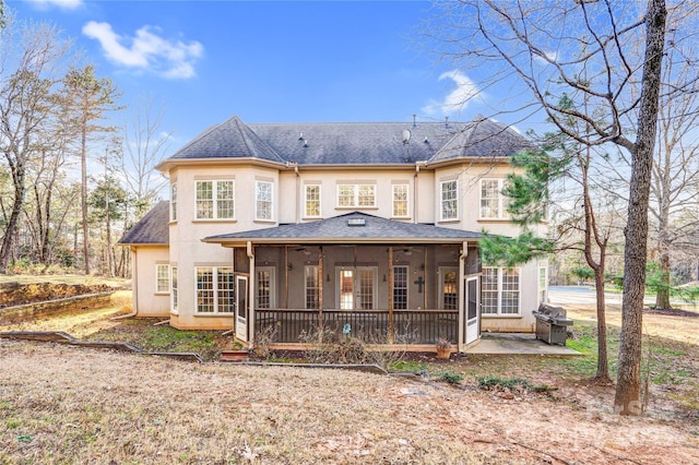 back of property with stucco siding, a patio, roof with shingles, and a sunroom