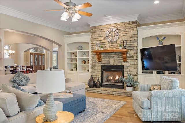 living area featuring wood finished floors, arched walkways, and ornamental molding