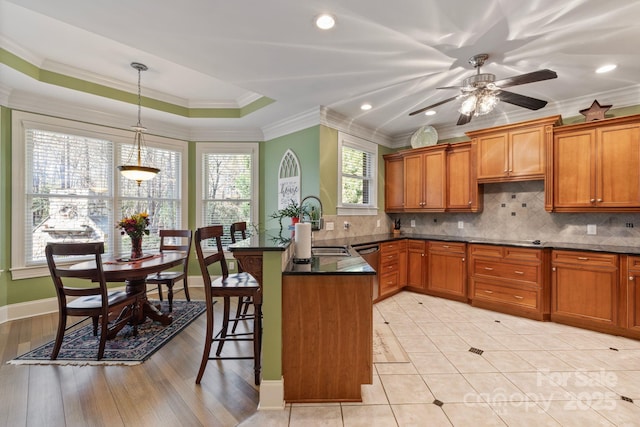 kitchen featuring a sink, a kitchen bar, a peninsula, and brown cabinetry