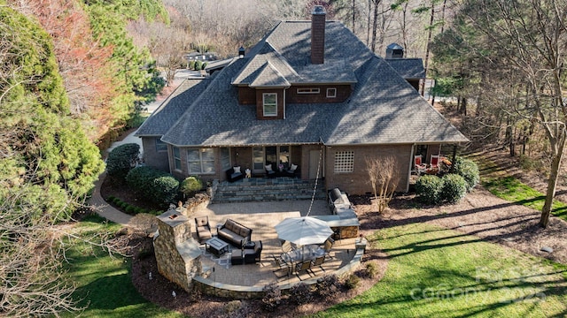 rear view of property with a yard, a patio area, brick siding, and a chimney