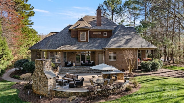 rear view of property featuring brick siding, a chimney, outdoor lounge area, a yard, and a patio