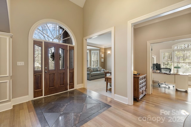 entrance foyer featuring wood finished floors, baseboards, and a towering ceiling