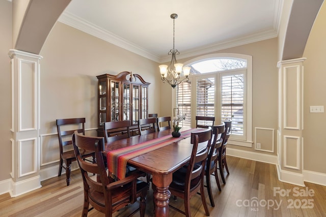 dining space with arched walkways, an inviting chandelier, ornate columns, and wood finished floors