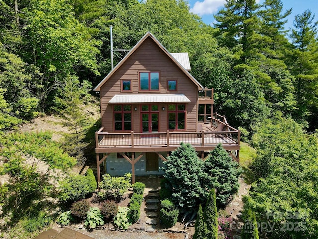 rustic home with metal roof, a deck, and a forest view