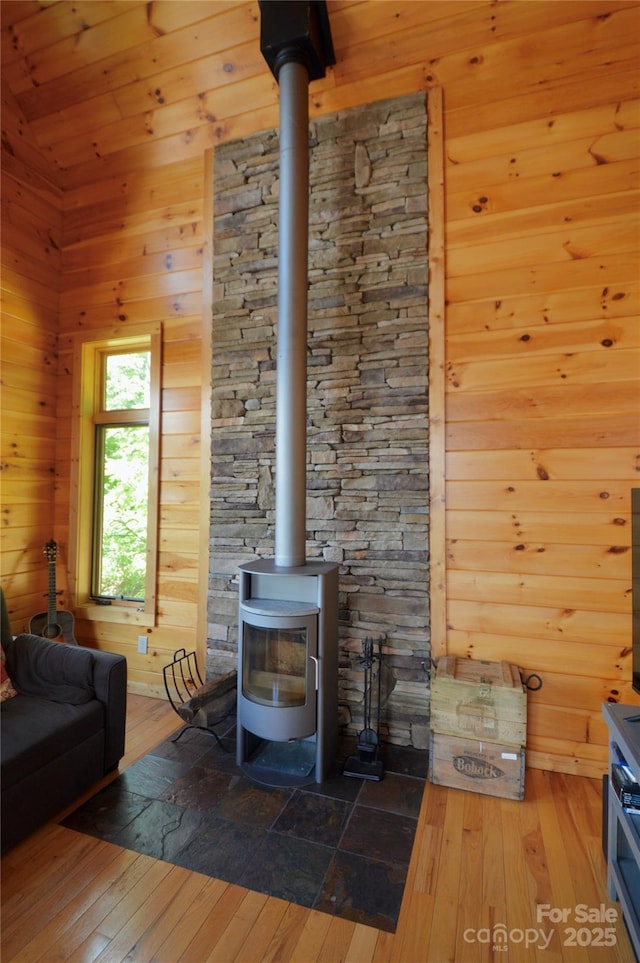 living area with a wood stove, wooden walls, hardwood / wood-style floors, and lofted ceiling