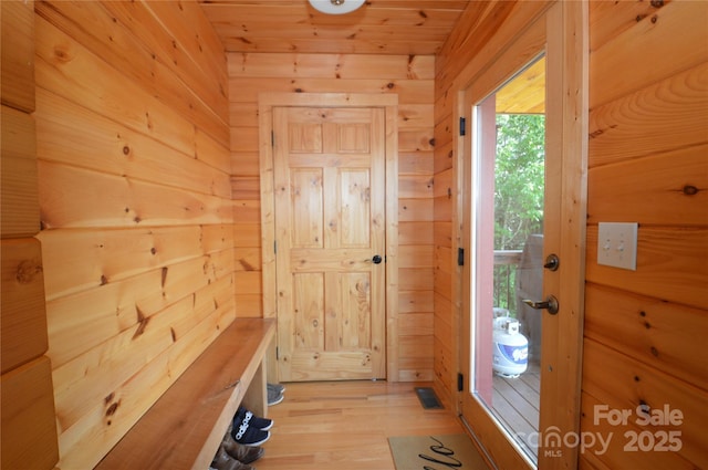 mudroom featuring light wood-type flooring, wood ceiling, and wooden walls