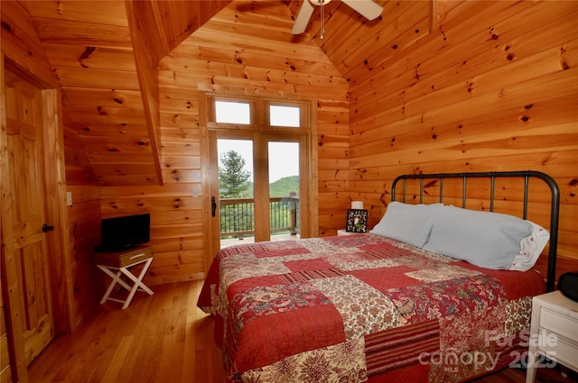 bedroom with access to outside, wood walls, lofted ceiling, and wood finished floors