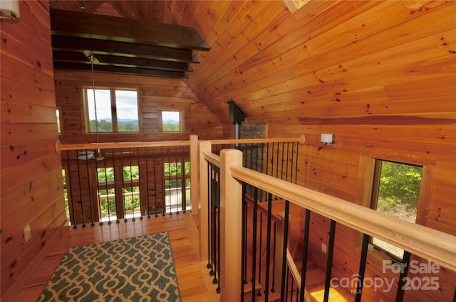 hallway with vaulted ceiling with beams, a wealth of natural light, wood ceiling, and wood walls