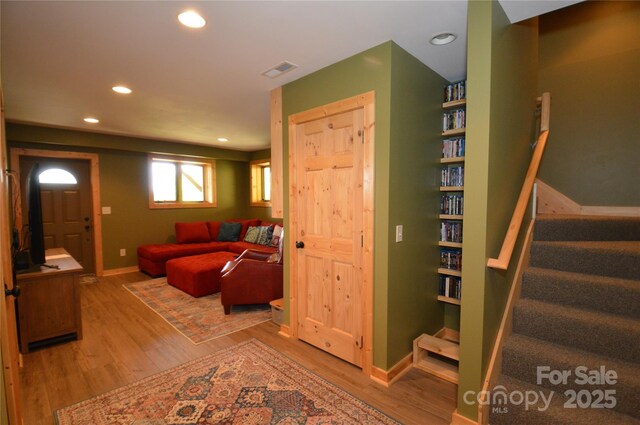 living area with stairs, recessed lighting, visible vents, and wood finished floors