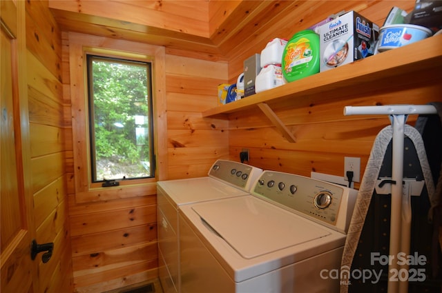 clothes washing area with laundry area, wood walls, and independent washer and dryer