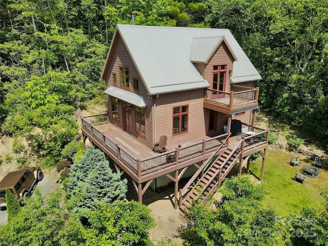 rear view of house featuring stairway, metal roof, a deck, a yard, and a wooded view