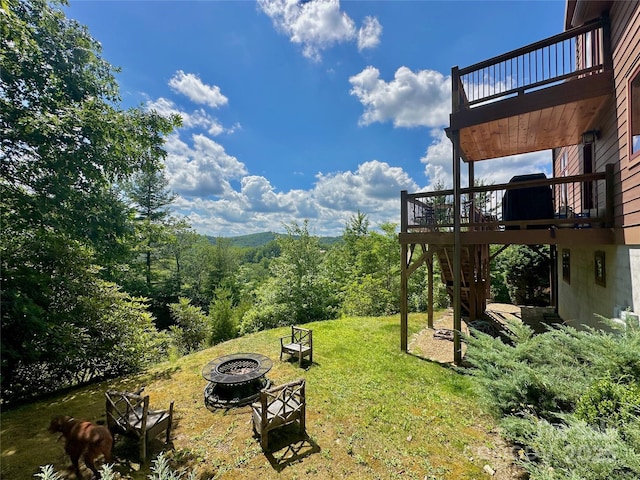 view of yard featuring an outdoor fire pit, a wooden deck, and a balcony