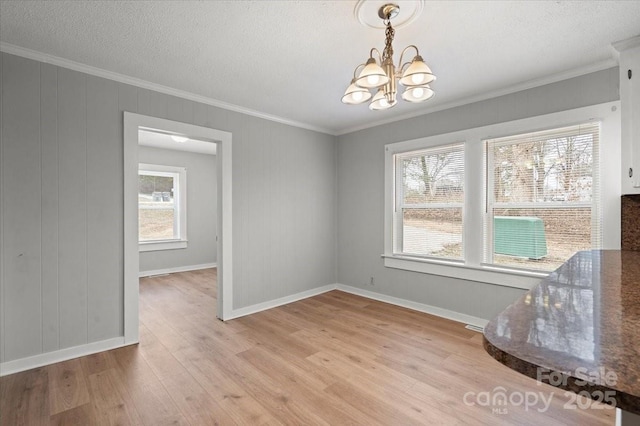 dining area with crown molding, a textured ceiling, an inviting chandelier, and light wood-style floors