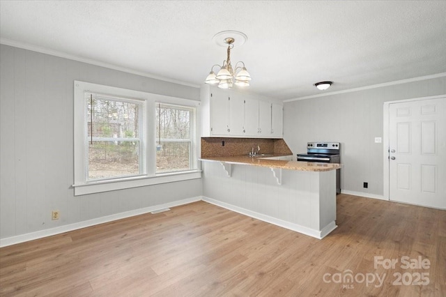 kitchen featuring light wood finished floors, white cabinets, stainless steel electric range oven, ornamental molding, and a peninsula