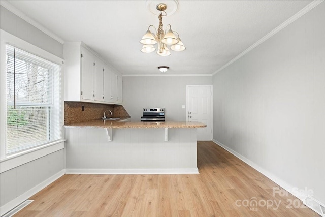 kitchen featuring a notable chandelier, light wood-style floors, white cabinets, stainless steel range with electric cooktop, and crown molding