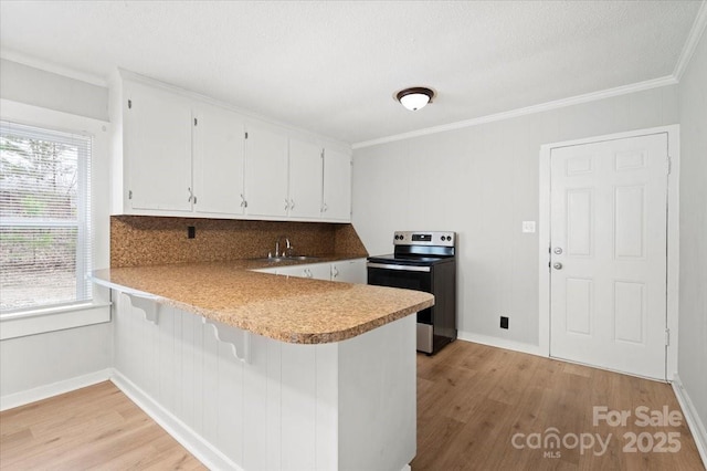 kitchen featuring a peninsula, light wood-style flooring, stainless steel range with electric stovetop, and white cabinetry