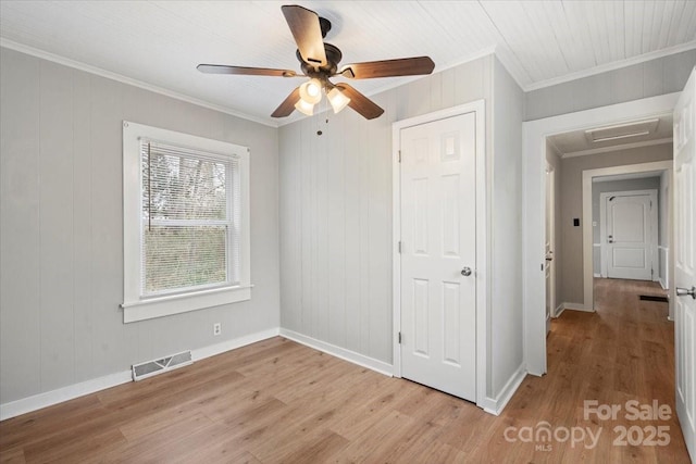 unfurnished bedroom with light wood-style floors, visible vents, crown molding, and baseboards