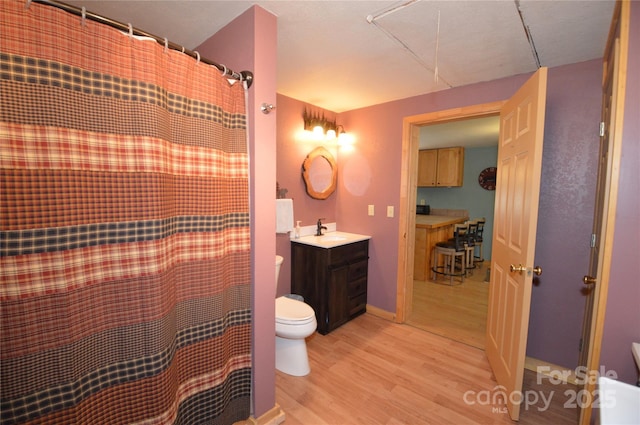 bathroom featuring toilet, curtained shower, wood finished floors, and vanity