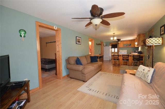 living room featuring baseboards, a ceiling fan, and light wood-style floors