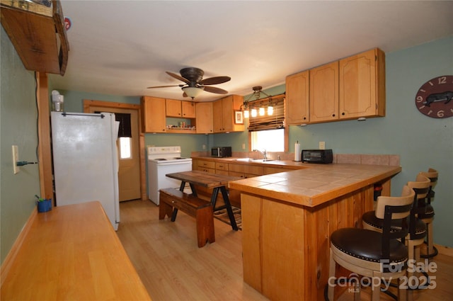 kitchen with electric range, light wood-style flooring, freestanding refrigerator, a peninsula, and a sink