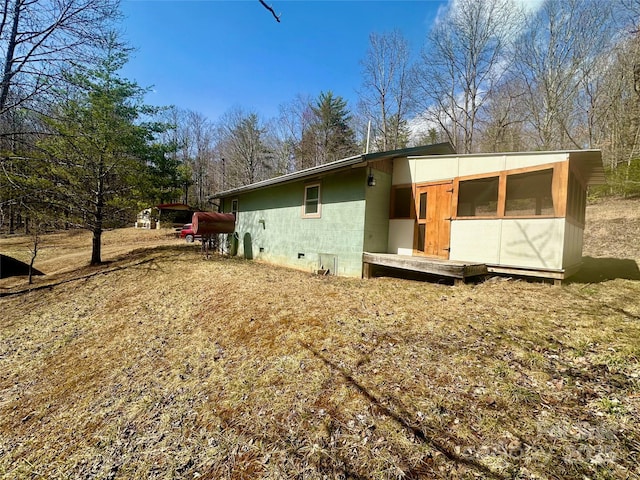 back of property with crawl space and concrete block siding