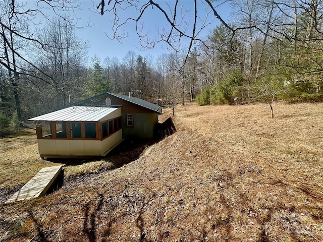 view of side of property featuring metal roof and a view of trees