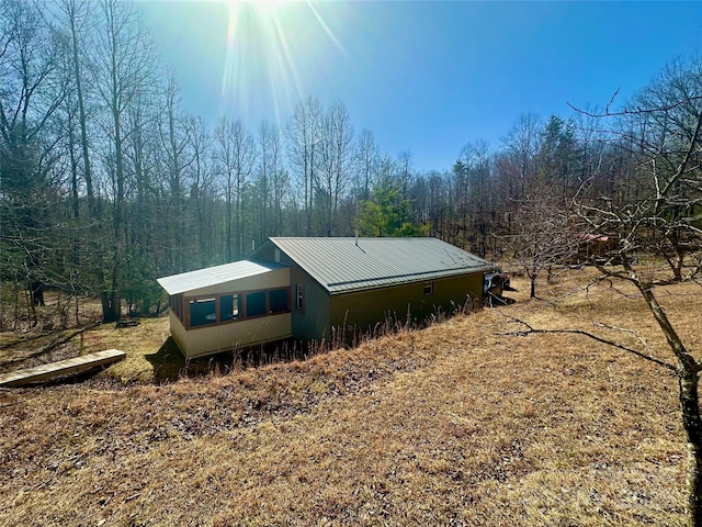 view of side of home with metal roof and a view of trees