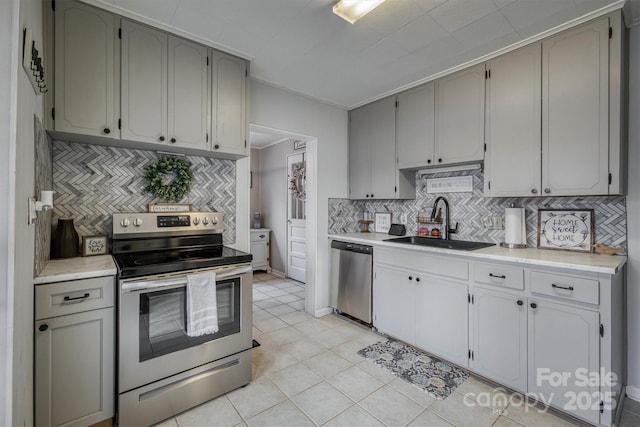 kitchen with decorative backsplash, appliances with stainless steel finishes, light countertops, and a sink