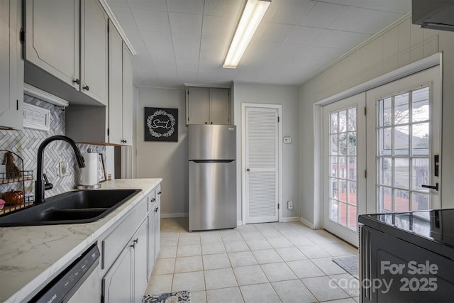 kitchen featuring a sink, tasteful backsplash, freestanding refrigerator, light tile patterned floors, and dishwasher