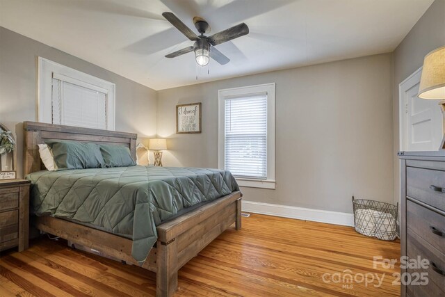 bedroom featuring a ceiling fan, baseboards, and light wood finished floors