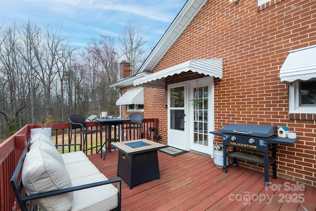 wooden terrace featuring an outdoor fire pit and a grill